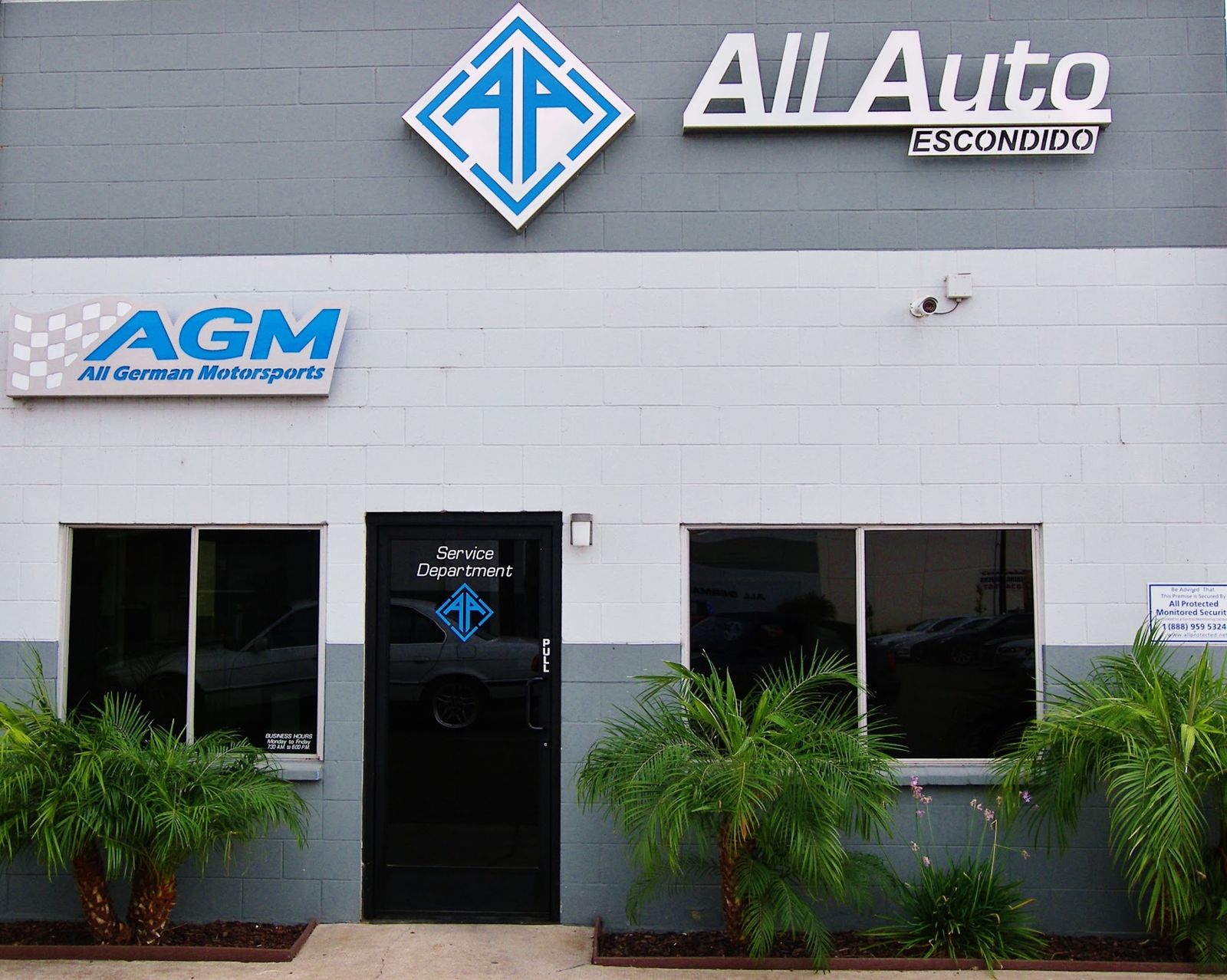 Front facade with the blue All Auto Escondido diamond sign above the entrance, framed by palms