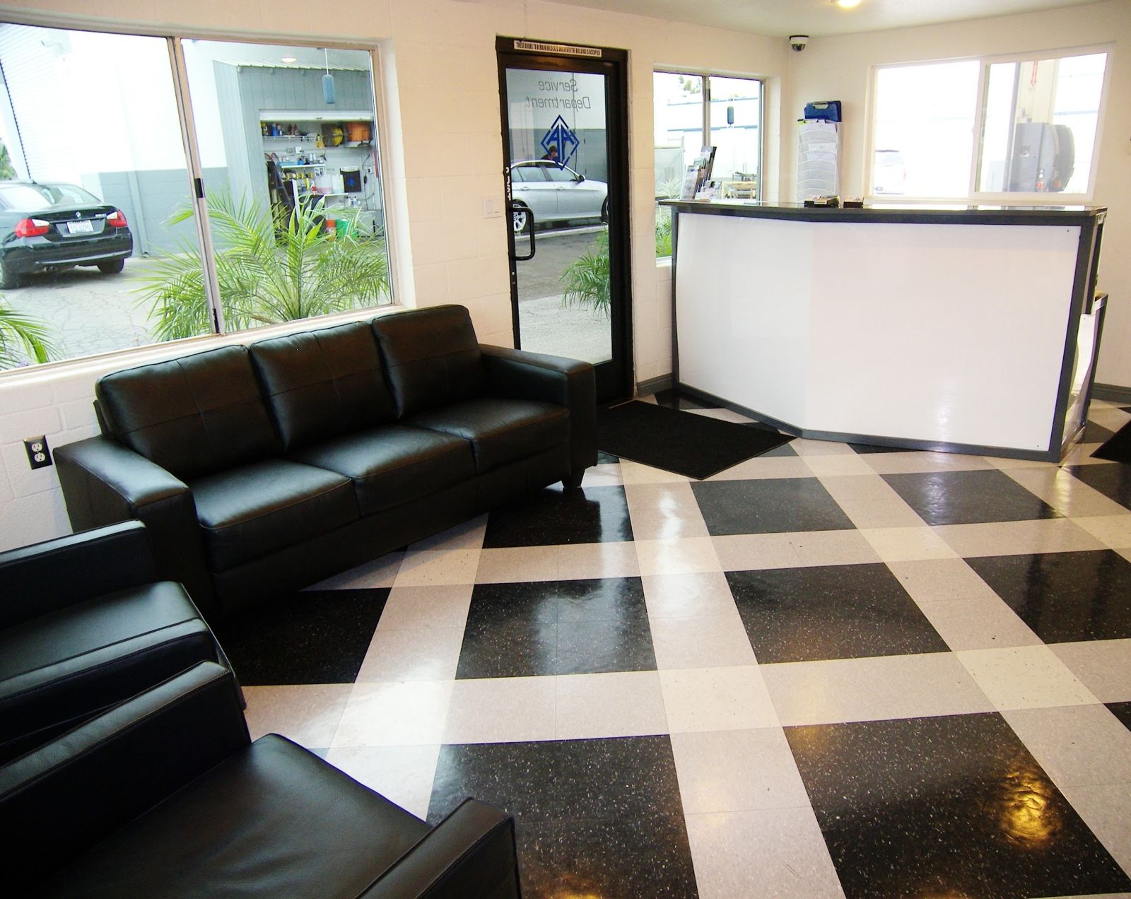 Customer lounge with black leather sofas and checkered tile floor